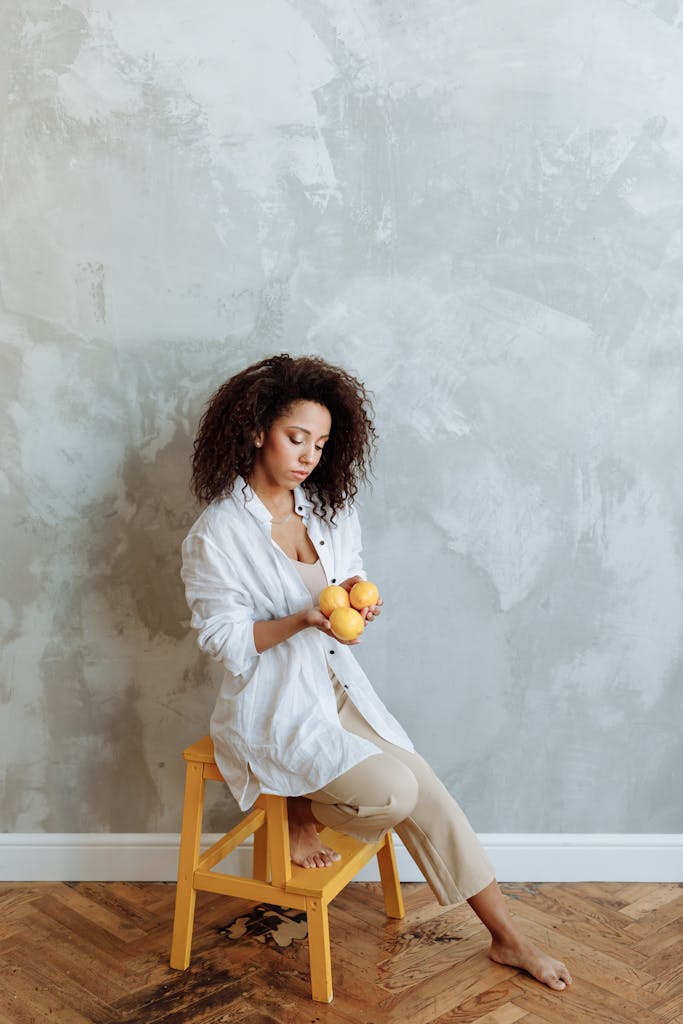 A Woman in White Long Sleeves Sitting on a Wooden Stool